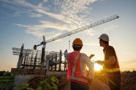 Engineers on a construction site with a crane at sunset